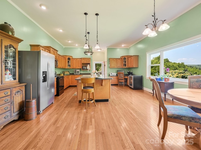 90 Coates Rd, Marshall, NC 28753 - kitchen with appliances with stainless steel finishes, brown cabinets, a center island with sink, a kitchen breakfast bar, and light wood-type flooring