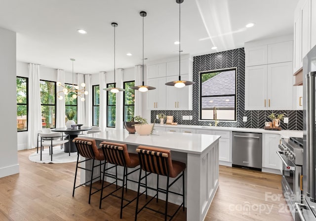 1626 Burtonwood Cir, Charlotte, NC 28212 - kitchen featuring appliances with stainless steel finishes, decorative backsplash, a kitchen island, light countertops, and white cabinets