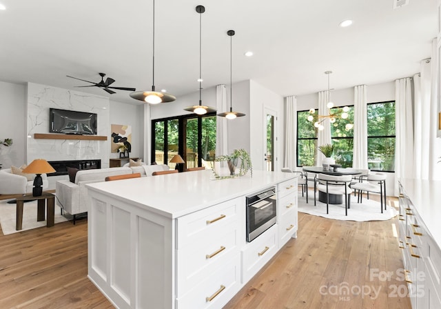 1626 Burtonwood Cir, Charlotte, NC 28212 - kitchen with stainless steel microwave, light wood-style floors, white cabinets, ceiling fan, and light countertops