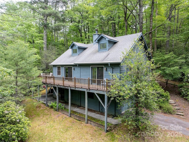 1396 W Christy Trl, Sapphire, NC 28774 - view of front of home with a chimney, a wooden deck, roof with shingles, and a wooded view