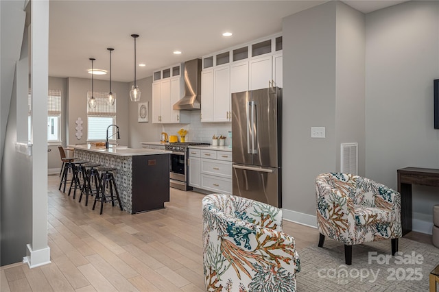 2011 Hamorton Pl, Charlotte, NC 28205 - kitchen featuring appliances with stainless steel finishes, wall chimney exhaust hood, an island with sink, baseboards, and recessed lighting
