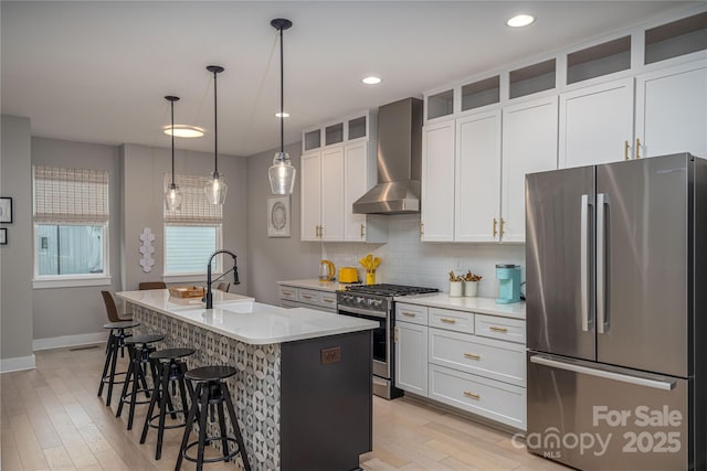 2011 Hamorton Pl, Charlotte, NC 28205 - kitchen featuring stainless steel appliances, wall chimney exhaust hood, a sink, an island with sink, and light wood finished floors
