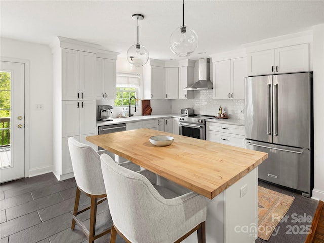 8 Rose Briar Cir, Weaverville, NC 28787 - kitchen featuring appliances with stainless steel finishes, wall chimney exhaust hood, butcher block counters, white cabinetry, and a breakfast bar