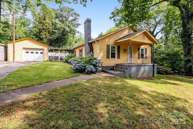 310 S Spencer Ave, Spencer, NC 28159 - view of front of property with a chimney, an outdoor structure, asphalt driveway, a front lawn, and a detached garage