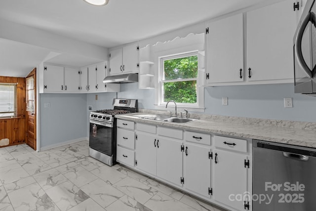 310 S Spencer Ave, Spencer, NC 28159 - kitchen with stainless steel appliances, under cabinet range hood, light marble finish flooring, light countertops, and wooden walls