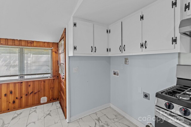 310 S Spencer Ave, Spencer, NC 28159 - kitchen with stainless steel gas stove, light marble finish floors, wood walls, wall chimney range hood, and white cabinets