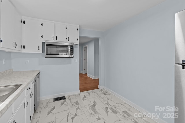 310 S Spencer Ave, Spencer, NC 28159 - kitchen with appliances with stainless steel finishes, light marble finish floors, white cabinetry, and light countertops