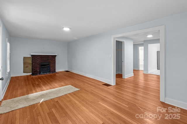 310 S Spencer Ave, Spencer, NC 28159 - unfurnished living room featuring a brick fireplace and light wood-style floors