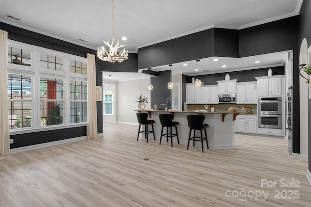 8725 Soaring Eagle Ln, Waxhaw, NC 28173 - kitchen with stainless steel appliances, a chandelier, crown molding, a breakfast bar, and tasteful backsplash