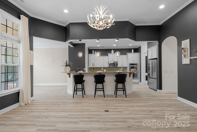 8725 Soaring Eagle Ln, Waxhaw, NC 28173 - kitchen featuring appliances with stainless steel finishes, a breakfast bar, light wood-style floors, tasteful backsplash, and a chandelier
