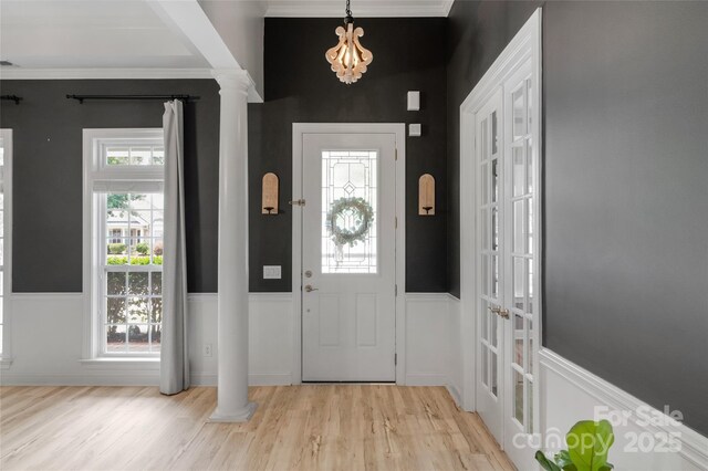 8725 Soaring Eagle Ln, Waxhaw, NC 28173 - foyer entrance featuring decorative columns, wainscoting, light wood-style floors, a chandelier, and crown molding