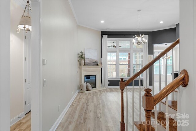 8725 Soaring Eagle Ln, Waxhaw, NC 28173 - staircase with wood finished floors, a chandelier, healthy amount of natural light, crown molding, and a glass covered fireplace