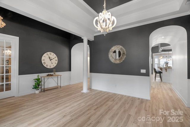 8725 Soaring Eagle Ln, Waxhaw, NC 28173 - empty room with decorative columns, wood finished floors, a chandelier, ornamental molding, and arched walkways