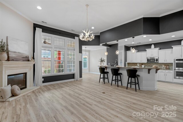 8725 Soaring Eagle Ln, Waxhaw, NC 28173 - kitchen with appliances with stainless steel finishes, a chandelier, a breakfast bar area, ornamental molding, and open floor plan