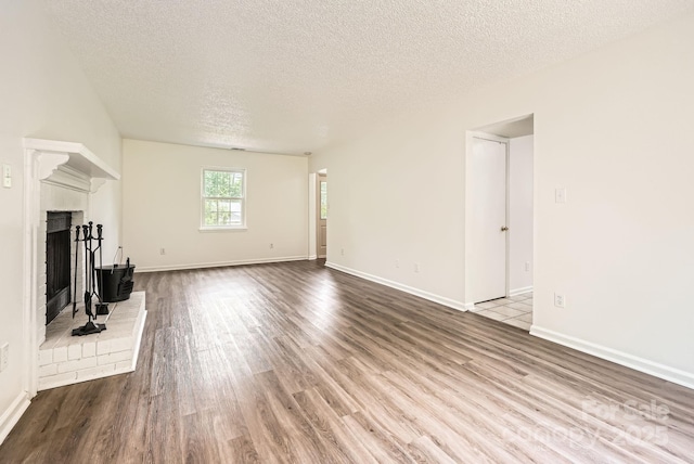 6221 Round Hill Rd, Charlotte, NC 28211 - unfurnished living room with a textured ceiling, wood finished floors, and a brick fireplace