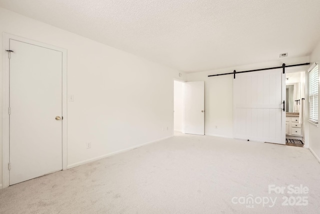 6221 Round Hill Rd, Charlotte, NC 28211 - unfurnished bedroom featuring carpet floors, a barn door, and a textured ceiling