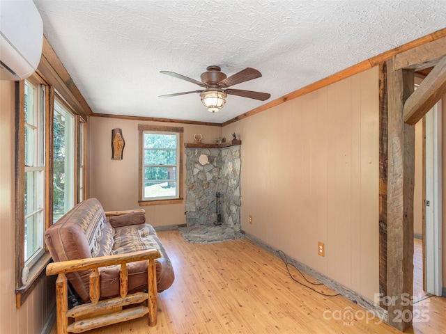 292 Cook Rd, Canton, NC 28716 - living area with light wood-style floors, ceiling fan, a wall mounted air conditioner, a textured ceiling, and a stone fireplace
