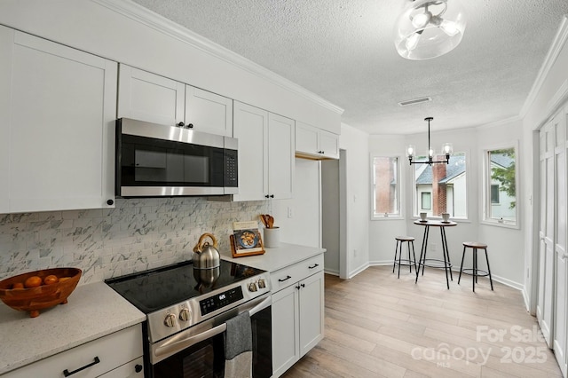 1035 Wexford Pl NW, Concord, NC 28027 - kitchen featuring appliances with stainless steel finishes, a textured ceiling, tasteful backsplash, a chandelier, and white cabinetry