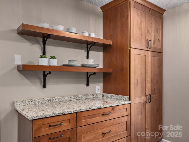 181 Junaluska Oaks Dr, Waynesville, NC 28786 - kitchen with open shelves, a textured ceiling, brown cabinetry, and light stone countertops