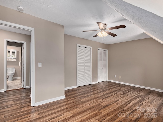 181 Junaluska Oaks Dr, Waynesville, NC 28786 - unfurnished bedroom with multiple closets, dark wood-type flooring, a textured ceiling, and ceiling fan