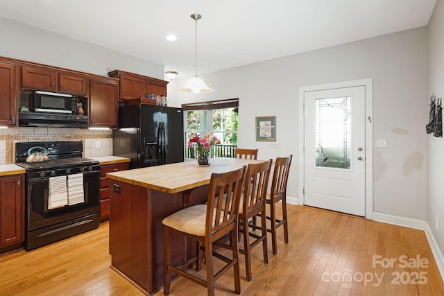 28 Richie St, Asheville, NC 28801 - kitchen featuring black appliances, wooden counters, range hood, backsplash, and a kitchen breakfast bar