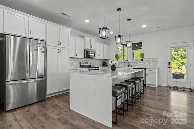 3127 Pinehills Way, Mount Holly, NC 28120 - kitchen featuring appliances with stainless steel finishes, dark wood-style flooring, backsplash, white cabinetry, and a kitchen island