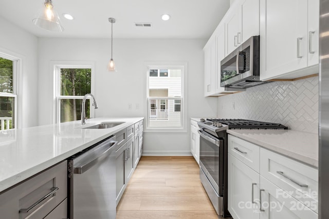 3924 Hager Dr, Charlotte, NC 28208 - kitchen with stainless steel appliances, a sink, tasteful backsplash, light wood-type flooring, and plenty of natural light