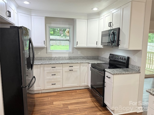 2015 Downey St, Rock Hill, SC 29732 - kitchen featuring freestanding refrigerator, black electric range oven, stainless steel microwave, light wood finished floors, and white cabinets