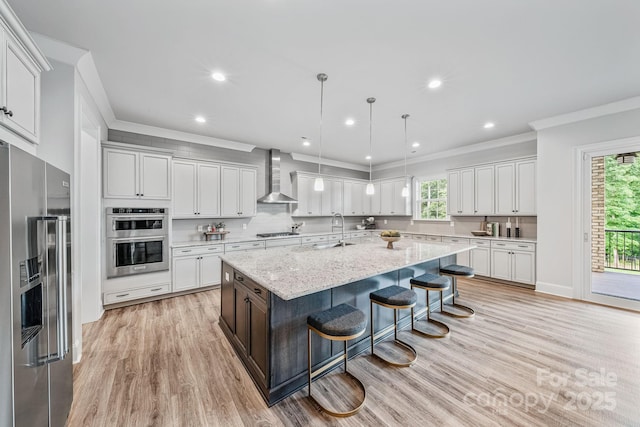 1702 Batson Creek Ln, Weddington, NC 28104 - kitchen featuring appliances with stainless steel finishes, wall chimney range hood, crown molding, a large island with sink, and a kitchen bar
