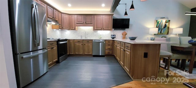 308 Woodfield Dr, Asheville, NC 28803 - kitchen with stainless steel appliances, a peninsula, under cabinet range hood, dark wood-type flooring, and a kitchen bar