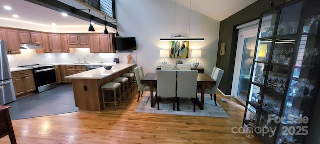 308 Woodfield Dr, Asheville, NC 28803 - kitchen featuring stainless steel appliances, under cabinet range hood, light wood finished floors, a peninsula, and a kitchen breakfast bar