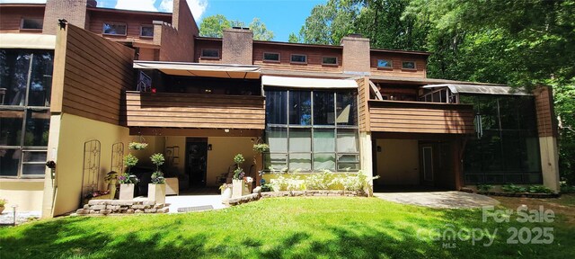 308 Woodfield Dr, Asheville, NC 28803 - rear view of property featuring stucco siding, a balcony, a lawn, and a chimney
