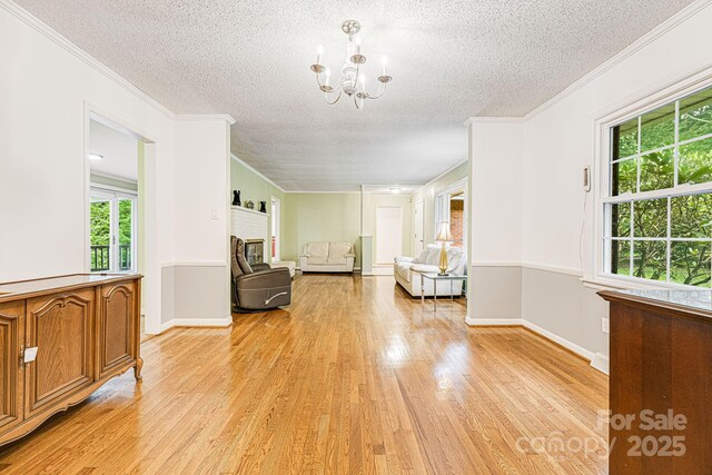 38 Westridge Dr, Asheville, NC 28803 - living area featuring a textured ceiling, light wood-style floors, a chandelier, ornamental molding, and baseboards
