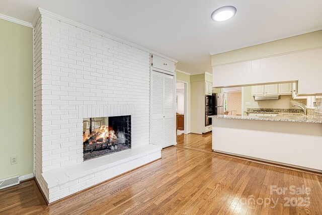 38 Westridge Dr, Asheville, NC 28803 - unfurnished living room with a fireplace, light wood finished floors, crown molding, and a sink