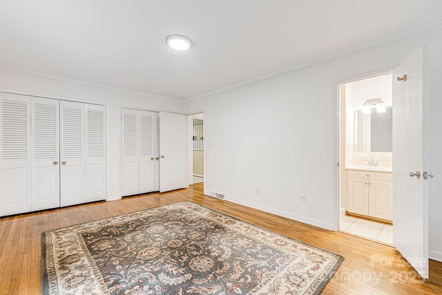 38 Westridge Dr, Asheville, NC 28803 - unfurnished bedroom with two closets, crown molding, hardwood / wood-style flooring, ensuite bathroom, and baseboards
