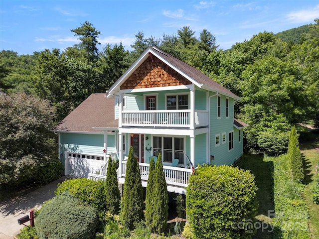 7 Oakhaven Ter, Asheville, NC 28803 - view of front facade featuring a porch, driveway, an attached garage, a wooded view, and a balcony