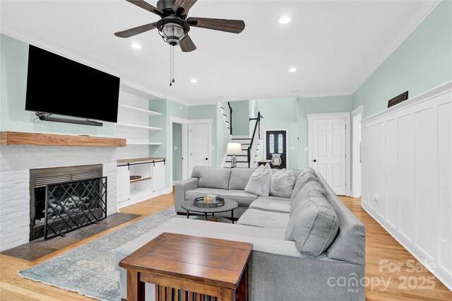 832 Kemp Rd, Mooresville, NC 28117 - living area with stairs, light wood-style floors, a ceiling fan, crown molding, and a fireplace