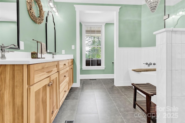 832 Kemp Rd, Mooresville, NC 28117 - bathroom featuring double vanity, a freestanding tub, a wainscoted wall, and tile patterned floors