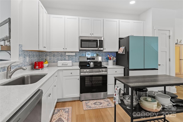 212 Rockrose Ct, Asheville, NC 28803 - kitchen featuring appliances with stainless steel finishes, a sink, white cabinetry, light wood-style flooring, and tasteful backsplash