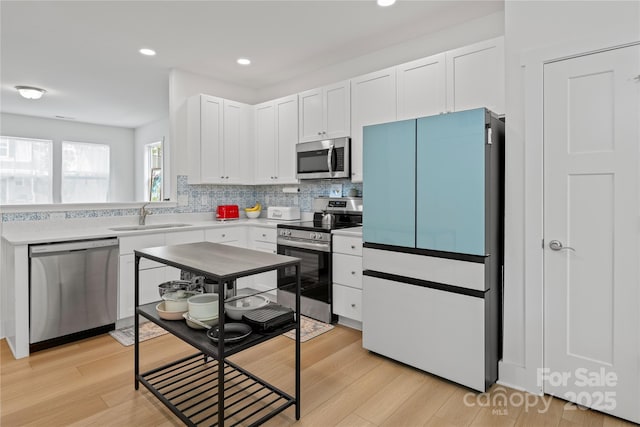 212 Rockrose Ct, Asheville, NC 28803 - kitchen with stainless steel appliances, a sink, white cabinetry, decorative backsplash, and light wood-type flooring