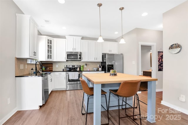 2210 Winding River Dr, Charlotte, NC 28214 - kitchen with appliances with stainless steel finishes, a sink, a kitchen bar, baseboards, and decorative backsplash