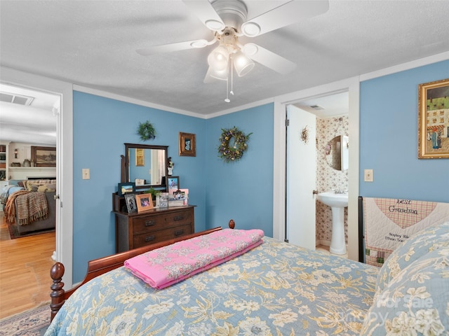 229 Crabtree Mountain Rd, Canton, NC 28716 - bedroom with wood finished floors, a ceiling fan, a textured ceiling, a sink, and ensuite bath