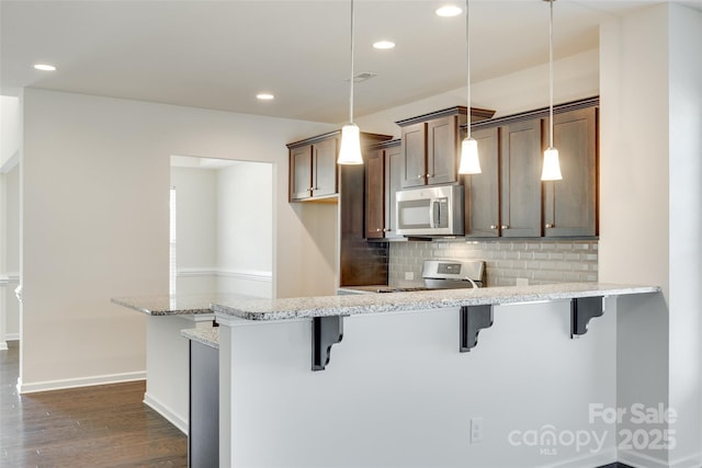 4051 Whittier Ln, Fort Mill, SC 29708 - kitchen featuring stainless steel appliances, a breakfast bar area, a peninsula, dark wood-style floors, and decorative backsplash