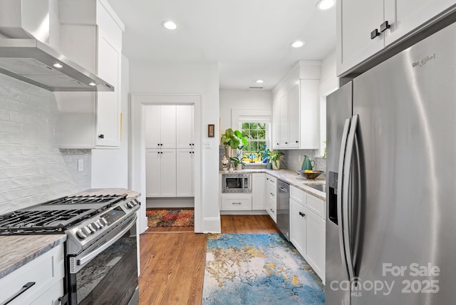 140 Pennsylvania Ave, Asheville, NC 28806 - kitchen with appliances with stainless steel finishes, wall chimney range hood, white cabinetry, recessed lighting, and decorative backsplash