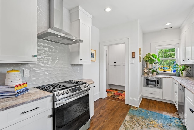 140 Pennsylvania Ave, Asheville, NC 28806 - kitchen featuring appliances with stainless steel finishes, wall chimney range hood, recessed lighting, white cabinets, and dark wood finished floors