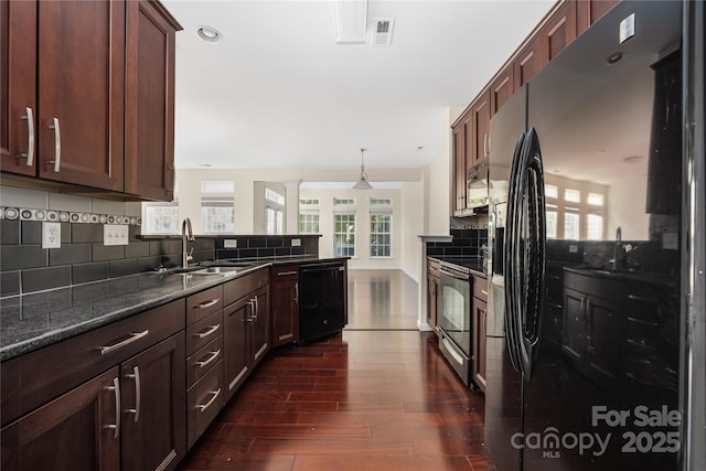6416 Union Station Ct, Charlotte, NC 28210 - kitchen featuring appliances with stainless steel finishes, dark wood-style floors, decorative backsplash, dark stone countertops, and a peninsula