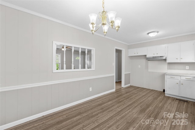 1812 Alpine Dr, Kings Mountain, NC 28086 - kitchen with wood finished floors, crown molding, under cabinet range hood, white cabinets, and a chandelier