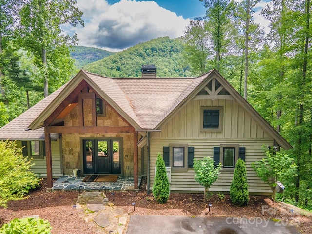 75 Indigo Bunting Ct, Tuckasegee, NC 28783 - view of front of house featuring board and batten siding, a chimney, a shingled roof, and a mountain view