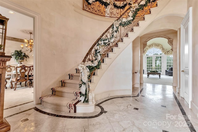1100 Glen Oaks Dr, Hamptonville, NC 27020 - foyer featuring inlaid floor details, arched walkways, a towering ceiling, stairs, and a chandelier
