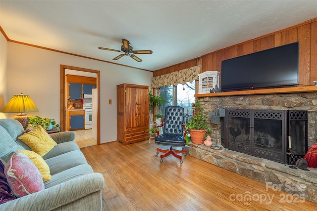 52 Oakhurst Rd, Arden, NC 28704 - living room featuring a stone fireplace, a ceiling fan, ornamental molding, wood finished floors, and wood walls